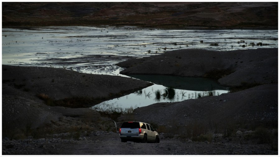 A car drives along a dirt road near Lake Mead.