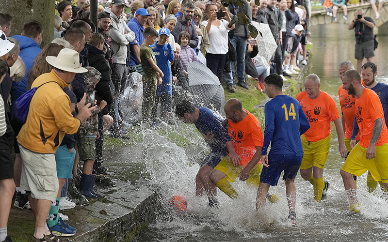 Footballers from Bourton Rovers fight for the ball during the annual traditional River Windrush football match