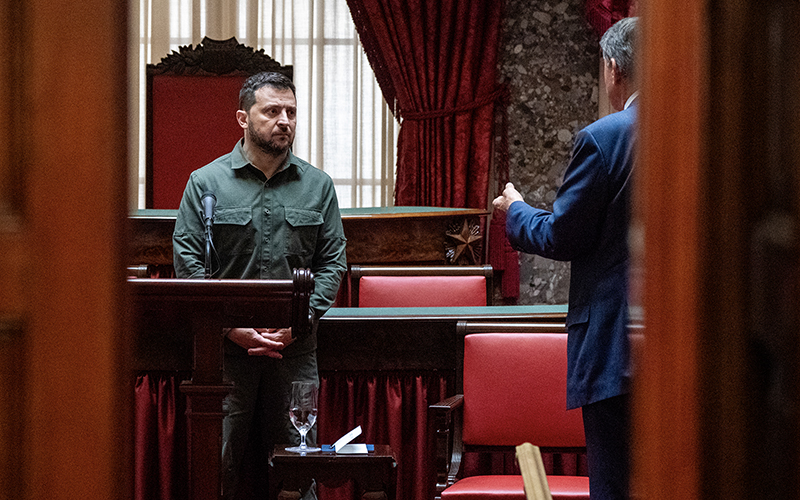 Ukrainian President Volodymyr Zelensky meets with all 100 Senators in the Old Senate Chamber of the Capitol September 21. Ukrainian President Volodymyr Zelensky is in Washington meeting with members of Congress. The photo is taken from an angle looking through a doorway at the meeting. Zelensky stands on the left, listening to a man who is standing on the right and partially obscured by the doorway.