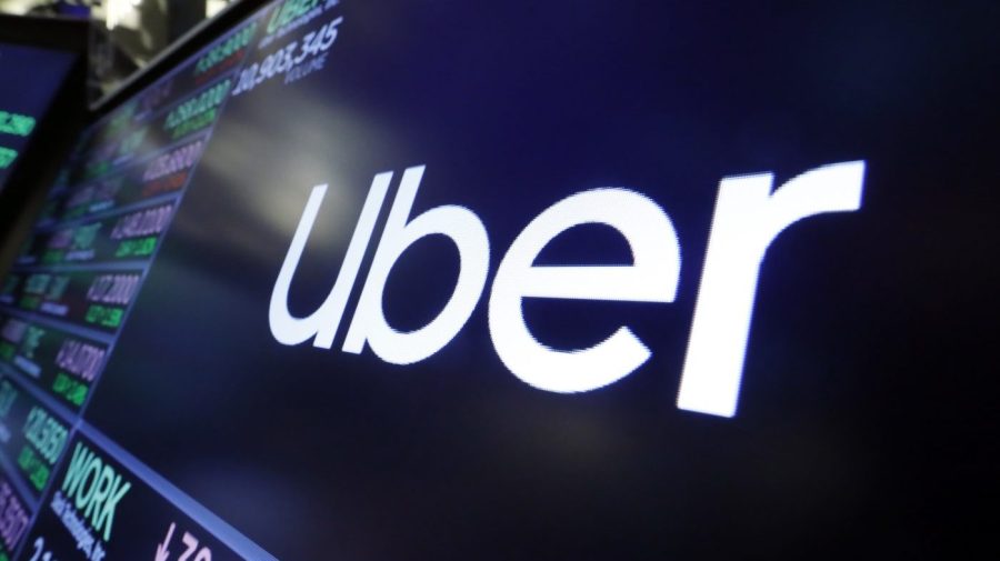 The logo for Uber appears above a trading post on the floor of the New York Stock Exchange, Aug. 16, 2019. The ride-hailing and delivery company said Wednesday, Oct. 4, 2023, that its drivers will collect up to five prepaid and sealed packages and drop them off at a local post office or at UPS or FedEx stores. Uber will charge a flat fee of $5 for the service or $3 for its Uber One members. (AP Photo/Richard Drew, File)