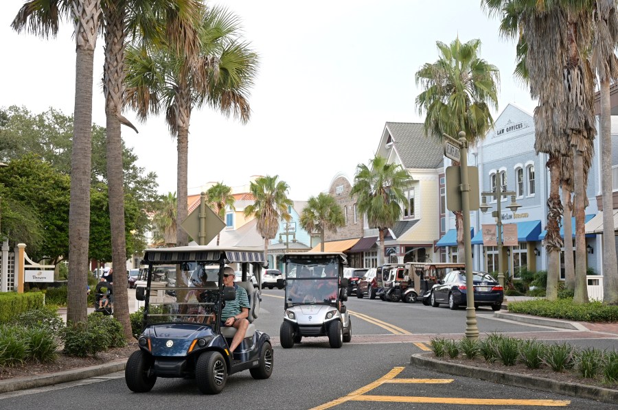 FILE - Residents drive golf carts through the Lake Sumter Landing Market Square on Aug. 12, 2021, in The Villages, Fla. A 77-year-old man in Florida has been arrested on a federal charge for obtaining misbranded erectile dysfunction drugs with the intent of distributing the medications throughout the enormous retirement community where he lives and elsewhere, authorities said. The man was arrested Sept. 2023, in The Villages, the sprawling retirement community of almost 80,000 fulltime residents in central Florida. (AP Photo/Phelan M. Ebenhack, File)