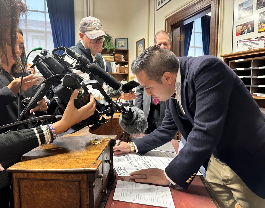 John Anthony Castro, of Texas, signs a commemorative poster after filing to get on the Republican ballot for the 2024 New Hampshire primary in Concord, N.H., on Wednesday, Oct. 11, 2023. Castro, who has filed multiple lawsuits contending the 14th Amendment bars former President Donald Trump's candidacy, wrote: "Freedom comes from our Constitution. Without that we fall." (AP Photo/Holly Ramer)