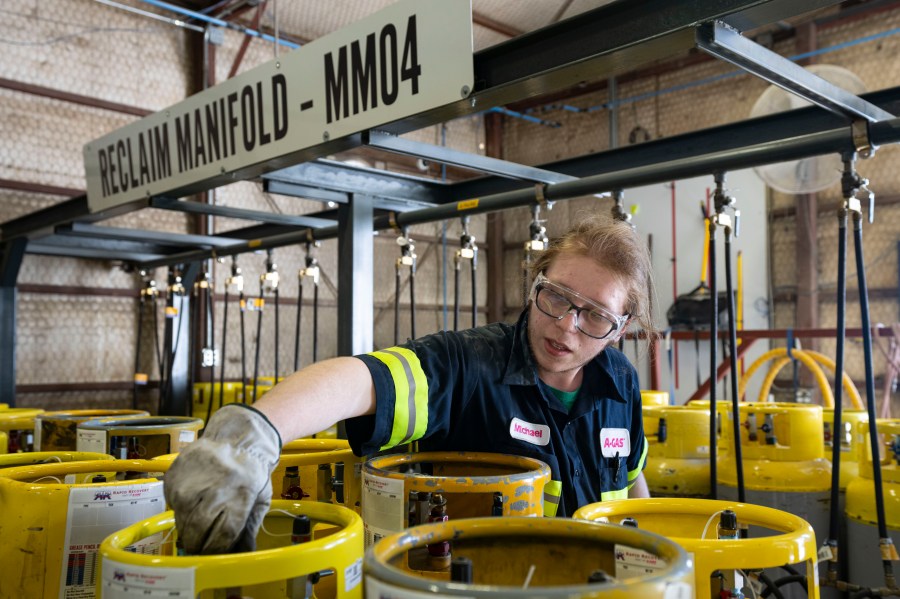 An operator prepares used cylinders to be drained of remaining refrigerant at the A-Gas Rhome facility on Monday, Oct. 9, 2023, in Rhome, Texas. The company takes in shipments of refrigerators and tanks from around the country and beyond, drains them, then purifies and reclaims the chemicals, shipping out recycled product. This prevents the need for new chemical production. (AP Photo/Sam Hodde)