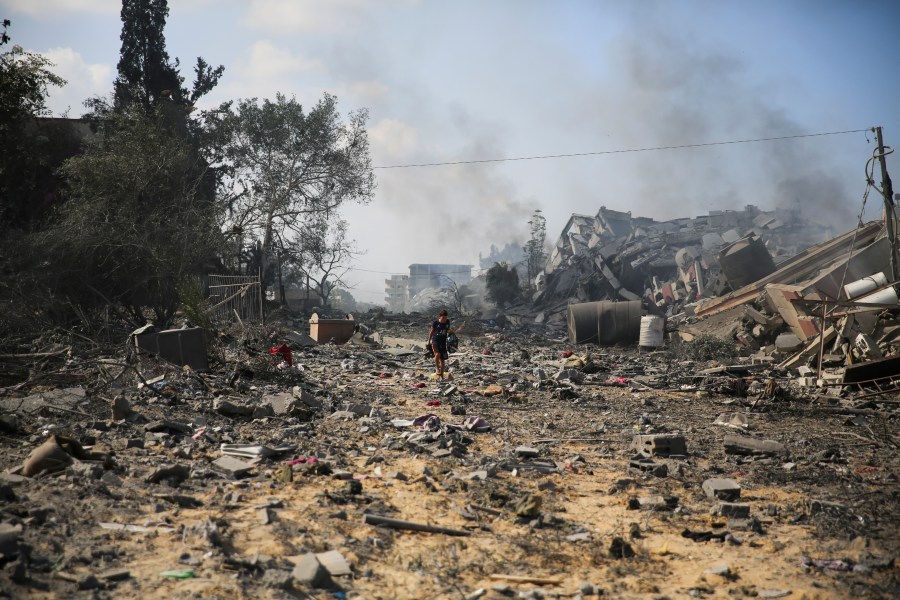 Palestinians boy walks by the buildings destroyed in the Israeli bombardment on al-Zahra, on the outskirts of Gaza City, Friday, Oct. 20, 2023. (AP Photo/Ali Mahmoud)