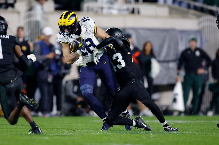 Michigan tight end Colston Loveland (18) is stopped by Michigan State defensive back Malik Spencer, right, during the first half of an NCAA college football game, Saturday, Oct. 21, 2023, in East Lansing, Mich. (AP Photo/Al Goldis)