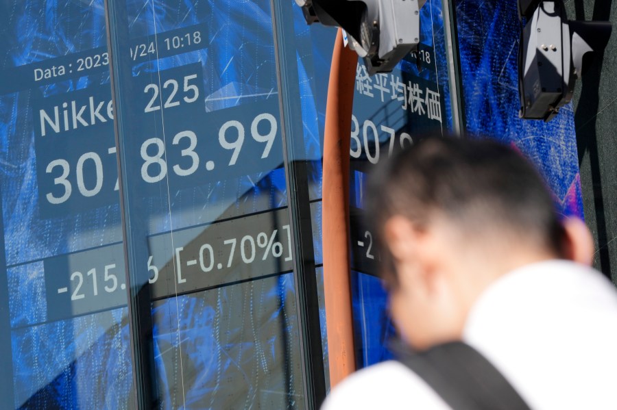 A person stands near an electronic stock board showing Japan's Nikkei 225 index at a securities firm Tuesday, Oct. 24, 2023, in Tokyo. Shares were mixed Tuesday in Asia after Wall Street wobbled to a mixed close as yields on U.S. Treasury bonds fell back after creeping above 5%. (AP Photo/Eugene Hoshiko)