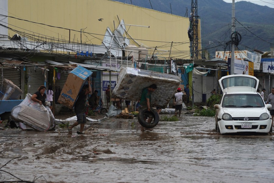 People carry away a mattress, a television monitor and a bicycle from a store at a shopping mall after Hurricane Otis ripped through Acapulco, Mexico, Wednesday, Oct. 25, 2023. Hurricane Otis ripped through Mexico's southern Pacific coast as a powerful Category 5 storm, unleashing massive flooding, ravaging roads and leaving large swaths of the southwestern state of Guerrero without power or cellphone service. (AP Photo/Marco Ugarte)