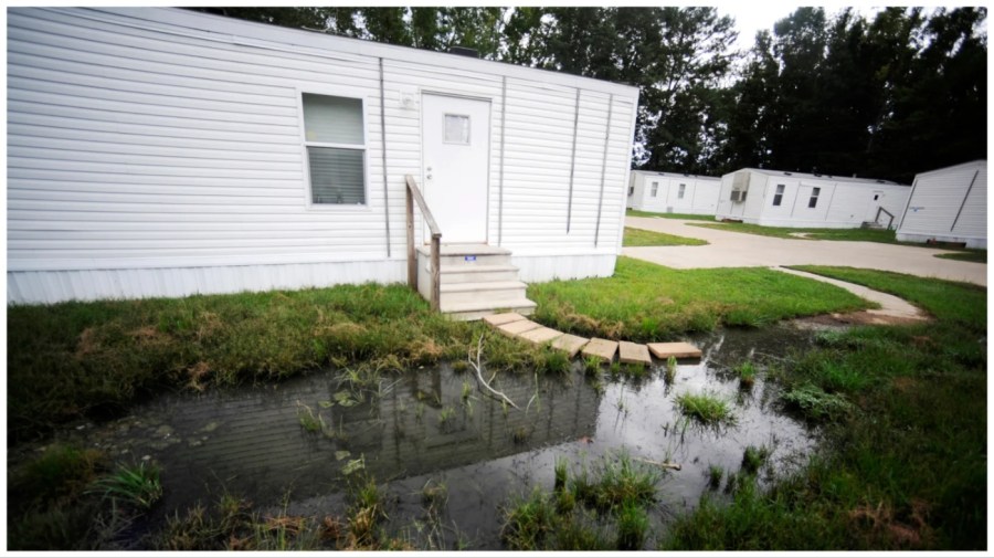 Fetid water stands outside a mobile home in a small mobile home park in rural Hayneville, Ala., on Monday, Aug. 1, 2022. The government announced a pilot program on Tuesday to help rural communities that face serious sewage problems like those in Lowndes County, where Hayneville is located. (AP Photo/Jay Reeves)