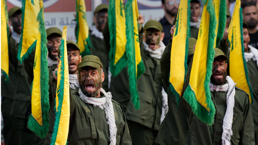 Hezbollah fighters rise their group flags and shout slogans, as they attend the funeral procession of their two comrades who were killed by Israeli shelling, in Kherbet Selem village, south Lebanon, Tuesday, Oct. 10, 2023. The Iran-backed group Monday night announced that three militants died following heavy Israeli shelling in border towns across southern Lebanon. (AP Photo/Hussein Malla)