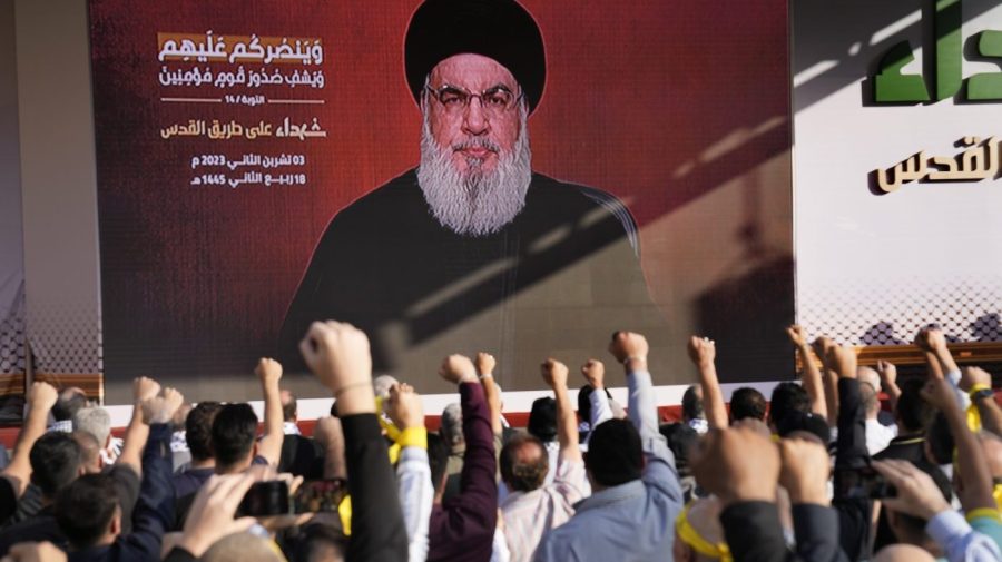 Supporters of the Iranian-backed Hezbollah group raise their fists and cheer as Hezbollah leader Sayyed Hassan Nasrallah appears via a video link, during a rally to commemorate Hezbollah fighters who were killed in South Lebanon last few weeks while fighting against the Israeli forces, in Beirut, Lebanon, Friday, Nov. 3, 2023. (AP Photo/Hussein Malla)