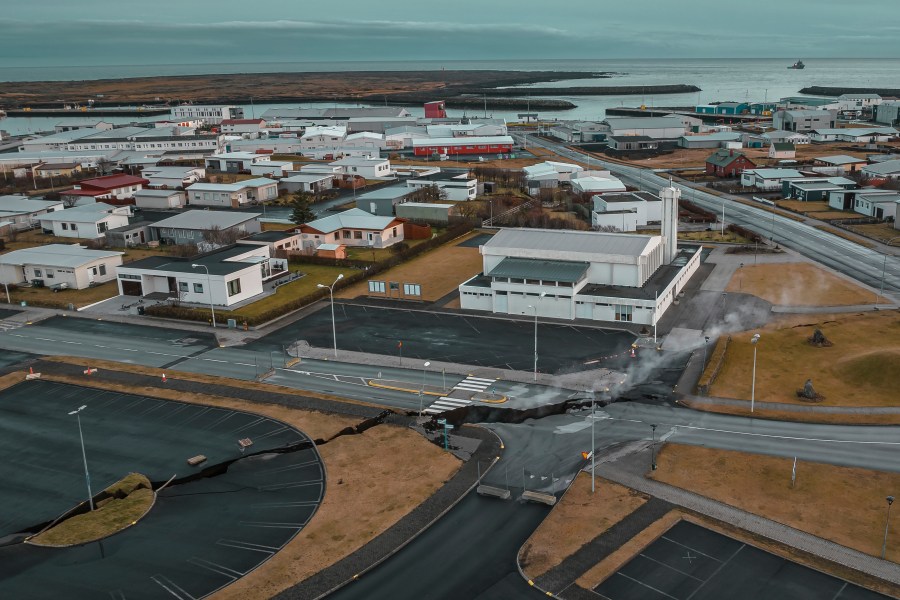 This image taken with a drone shows the town of Grindavik, Iceland, as a Coast Guard vessel patrol, Thursday, Nov. 16, 2023. Residents of a fishing town in southwestern Iceland have left their homes after increasing concern about a potential volcanic eruption caused civil defense authorities to declare a state of emergency in the region. Iceland's Meteorological Office says police decided to evacuate Grindavik after recent seismic activity in the area moved south toward the town. (AP Photo/Bjorn Steinbekk)