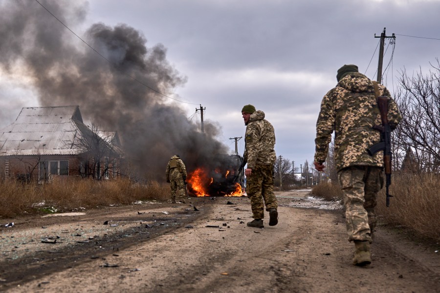 In this photo provided by the Ukrainian 10th Mountain Assault Brigade "Edelweiss", Ukrainian soldiers pass by a volunteer bus burning after a Russian drone hit it near Bakhmut, Donetsk region, Ukraine, Thursday, Nov. 23, 2023. (Shandyba Mykyta, Ukrainian 10th Mountain Assault Brigade "Edelweiss" via AP)