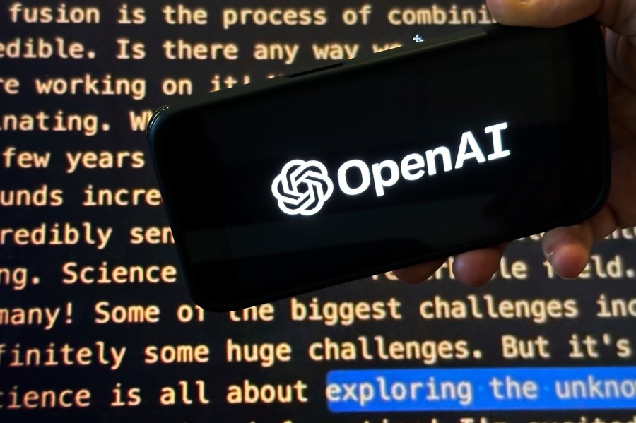 FILE - The OpenAI logo appears on a mobile phone in front of a screen showing a portion of the company website, Tuesday, Nov. 21, 2023, in New York. Sports Illustrated is the latest media company damaged by being less than forthcoming about who or what is writing its stories. The website Futurism reported that the once-grand magazine used articles with “authors” who apparently don't exist, with photos generated by AI. The magazine denied claims that some articles themselves were AI-assisted, but has cut ties with a vendor it hired to produce the articles. (AP Photo/Peter Morgan, File)