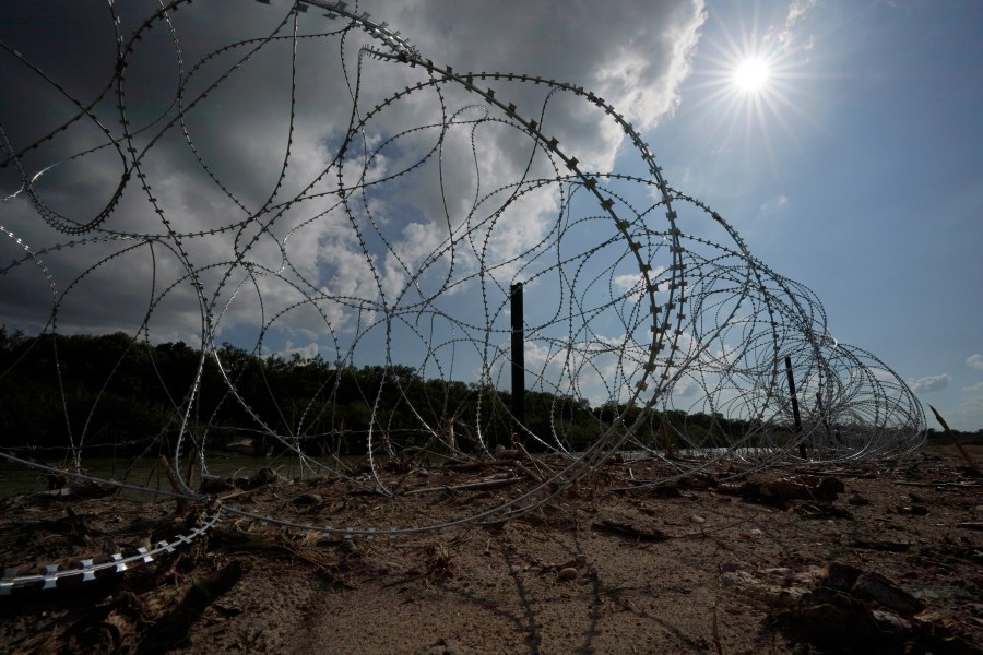 FILE - Concertina wire lines the banks of the Rio Grande on the Pecan farm of Hugo and Magali Urbina, near Eagle Pass, Texas, Monday, July 7, 2023.