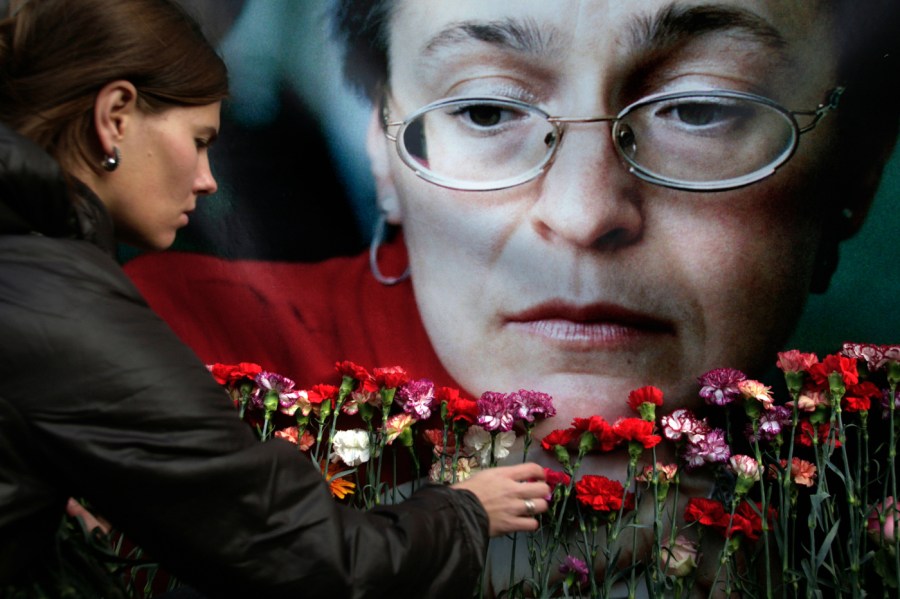 In this Oct. 7, 2009 file photo, a woman places flowers before a portrait of slain Russian journalist Anna Politkovskaya, in Moscow.