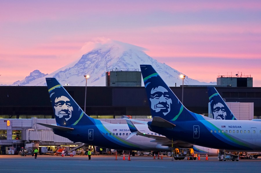 FILE - Alaska Airlines planes are shown parked at gates with Mount Rainier in the background at sunrise, March 1, 2021, at Seattle-Tacoma International Airport in Seattle. Alaska Air Group said Sunday, Dec. 3, 2023, that it agreed to buy Hawaiian Airlines in a $1 billion deal. (AP Photo/Ted S. Warren, File)