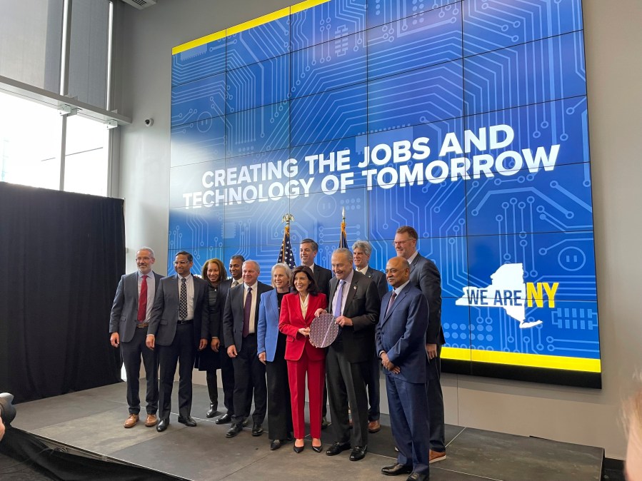 New York Gov. Kathy Hochul and Sen. Chuck Schumer hold a silicon wafer and pose for a photo with lawmakers and leaders from the semiconductor industry during an event at University at Albany in Albany, New York, Monday, Dec. 11, 2023. New York will spend $1 billion to expand research into chip technology in Albany, the state's capital, with the goal of turning the region into a global center of semiconductor research and manufacturing, Gov. Kathy Hochul announced Monday. (AP Photo/Maysoon Khan)