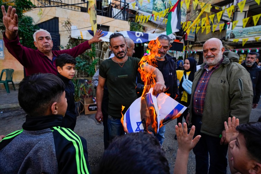 Palestinians burn Israeli flags, during the observance of a global day of boycotts and strikes called for by pro-Palestinian activists to demand a cease-fire in Gaza, at Bourj al-Barajneh Palestinian refugee camp in Beirut, Lebanon, Monday, Dec. 11, 2023. Public agencies, schools and banks were shuttered in Lebanon Monday in observance of a global day of boycotts and strikes called for by pro-Palestinian activists to demand a ceasefire in Gaza. (AP Photo/Bilal Hussein)