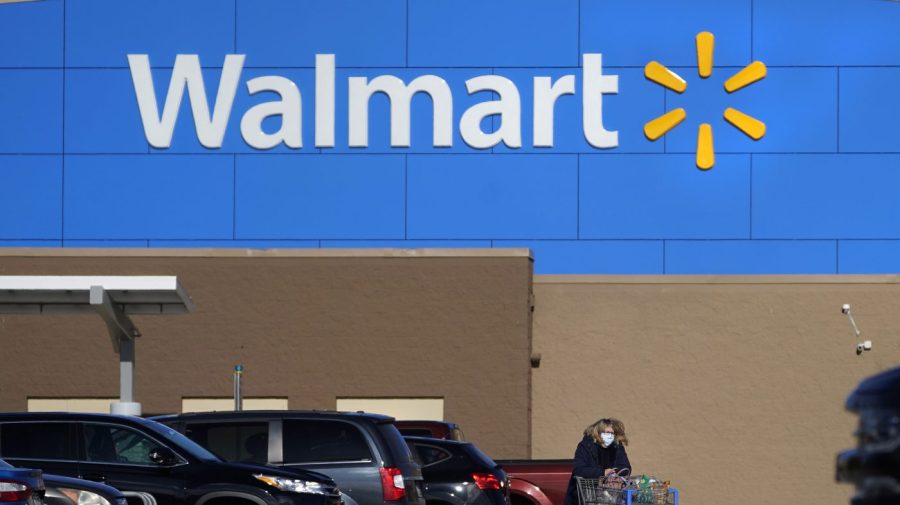 FILE - A woman wheels a cart with her purchases out of a Walmart store, Nov. 18, 2020, in Derry, N.H. (AP Photo/Charles Krupa, File)