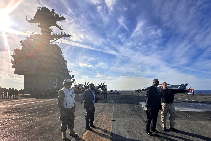 Defense Secretary Lloyd Austin, second right, talks with the commanding officer of the USS Gerald R. Ford, Navy Capt. Rick Burgess, right, during an unannounced visit to the ship on Wednesday, Dec. 20, 2023. The USS Gerald R. Ford has been sailing just a few hundred miles off the coast of Israel to prevent the Israel-Hamas war from expanding into a regional conflict. (AP Photo/Tara Copp)