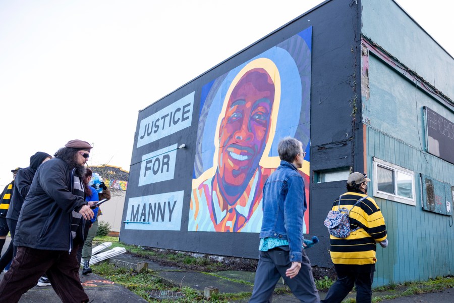Protestors walk by a mural of Manny Ellis after the verdict is read during the trial of three Tacoma Police officers in the killing of Manny Ellis, at Pierce County Superior Court, Thursday, Dec. 21, 2023, in Tacoma, Wash. A jury cleared three Washington state police officers of all criminal charges Thursday, Dec. 21, 2023 in the 2020 death of Manuel Ellis, a Black man who was shocked, beaten and restrained face down on a Tacoma sidewalk as he pleaded for breath.. (AP Photo/Maddy Grassy)