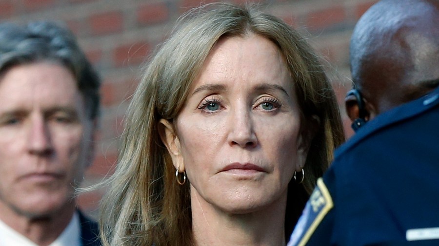 FILE — In this Friday, Sept. 13, 2019, file photo, Felicity Huffman leaves federal court in Boston with her brother Moore Huffman Jr., background left, after she was sentenced in a nationwide college admissions bribery scandal.