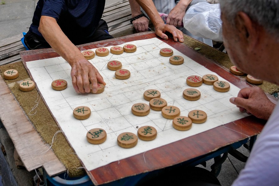 FILE - Residents play Chinese chess games outside a residential area in Beijing on July 19, 2021. A competitor in Chinese chess says he has sued the national association in China for mental distress after he was stripped of a title for drinking alcohol and defecating in the bathtub of his hotel room at a recent competition. Yan Chenglong 's complaint — which demands that the association apologize, restore his reputation in the media and pay him 100,000 yuan ($14,000) in damages — was mailed to a court in central China's Henan province on Monday, Jan. 1, 2024, according to a post on Yan's social media account. (AP Photo/Andy Wong, File)