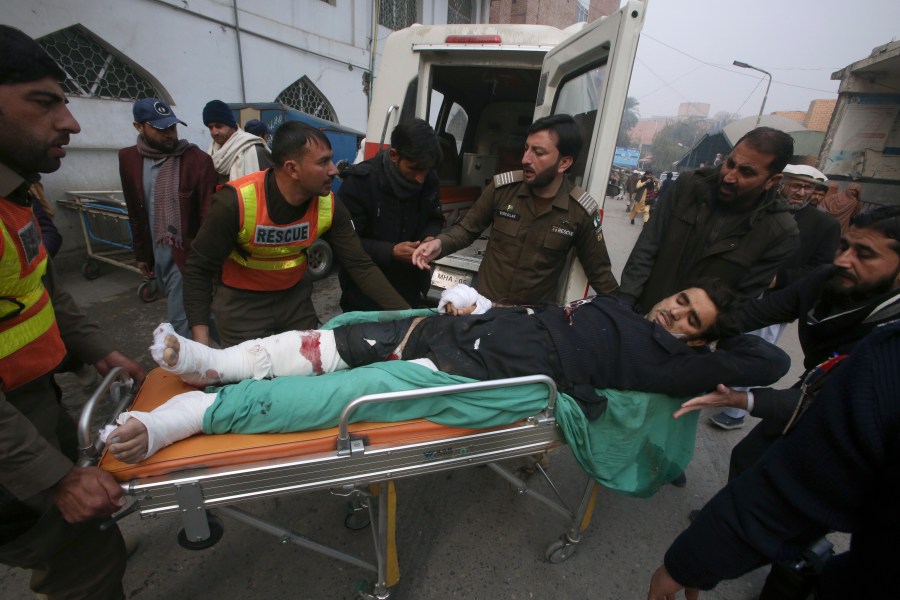 Rescue workers and volunteers transport an injured police officer, a victim of roadside bombing, upon arrival at a hospital in Peshawar, Pakistan, Monday, Jan. 8, 2024. A roadside bomb exploded Monday near a van carrying police assigned to protect workers in an anti-polio immunization campaign in restive northwestern Pakistan, killing and wounding officers and others, officials said. (AP Photo/Muhammad Sajjad)