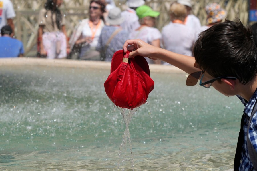 FILE - A child plunges his hat into a fountain on a hot day as he waits for the start of Pope Francis' Angelus prayer in St. Peter's Square at the Vatican, July 16, 2023. Earth last year shattered global annual heat records, the European climate agency said Tuesday, Jan. 9, 2024. (AP Photo/Gregorio Borgia, File)