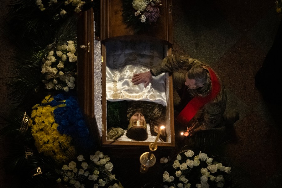 A Ukrainian army chaplain pays his respects at the coffin of Ukrainian serviceman and famous Ukrainian poet Maksym Kryvtsov, who was killed in a battle with the Russian troops, during the funeral ceremony in St. Michael Cathedral in Kyiv, Ukraine, Thursday, Jan. 11, 2024. (AP Photo/Efrem Lukatsky)