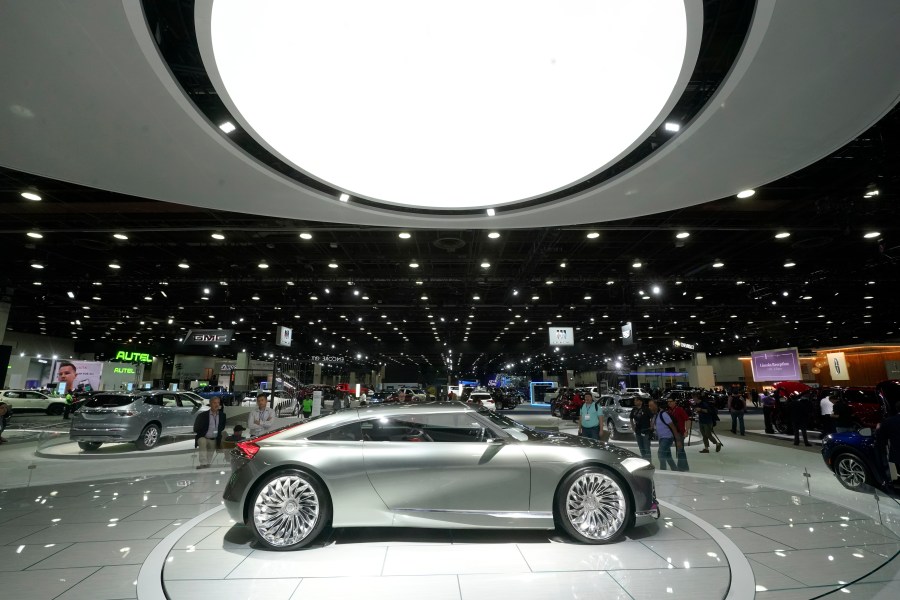 An concept electric vehicle model is displayed on a large platform during a car show.