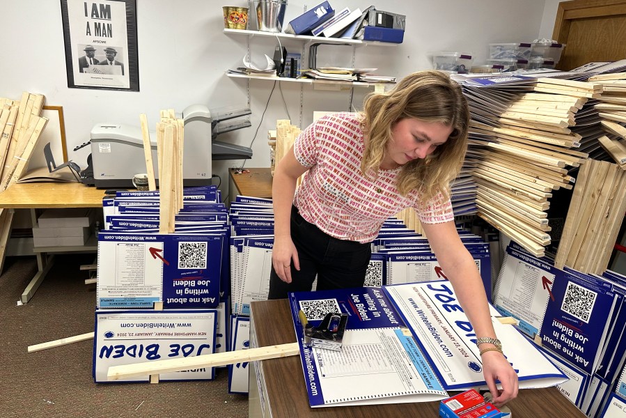 Emily Vering, a 20-year-old volunteer and sophomore at St. Olaf College, assembles a yard sign as part of a course she is taking on campaigns and politics in Hooksett, N.H., Wednesday, Jan. 17, 2024. President Joe Biden is skipping the New Hampshire Democratic primary on Tuesday because it doesn't comply with party rules, but some supporters have begun a campaign to get voters to write-in his name on the ballot. (AP Photo/Will Weissert)