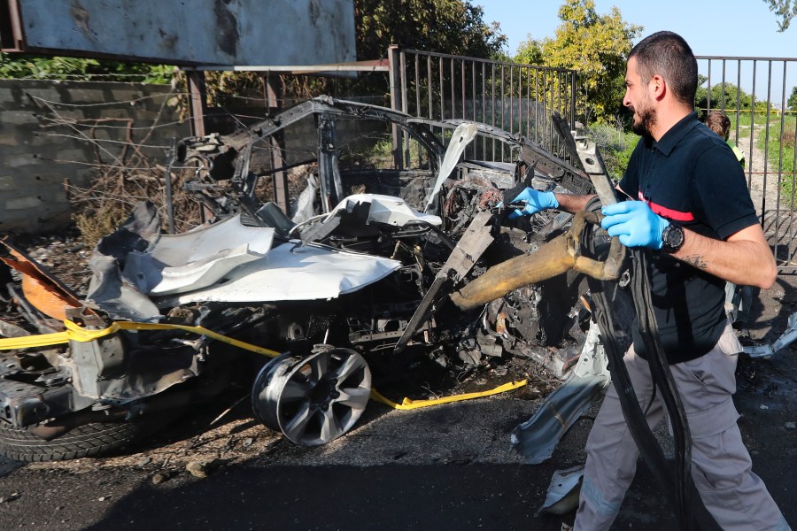 A civil defense worker carries parts of a destroyed car in the southern town of Bazouriyeh, Lebanon, Saturday, Jan. 20, 2024. An Israeli drone strike on the car near the Lebanese southern port city of Tyre killed two people, the state-run National News Agency reported. (AP Photo/Mohammad Zaatari)