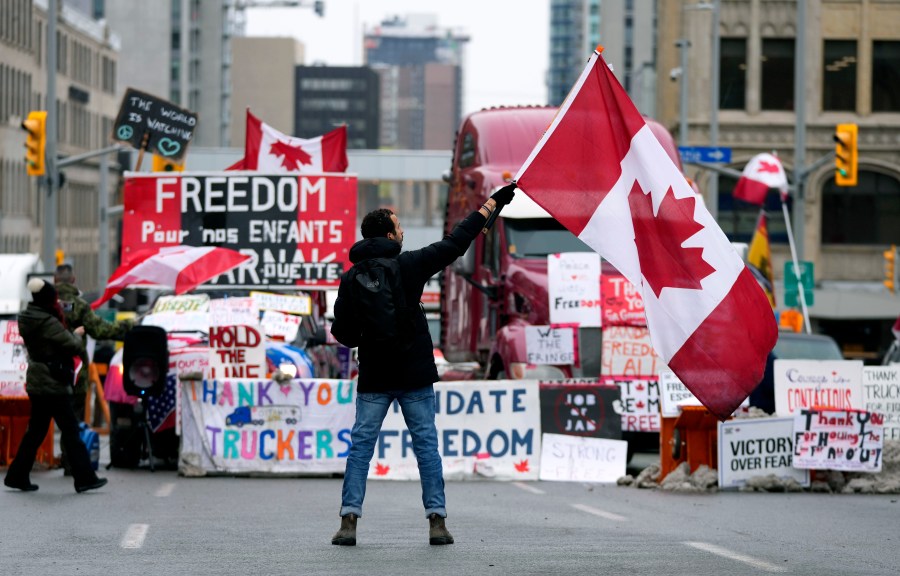 FILE - A protester waves a Canadian flag in front of parked vehicles at a protest against COVID-19 measures that has grown into a broader anti-government protest, in Ottawa, Ontario, Feb. 11, 2022. In a decision released Tuesday, Jan. 23, 2024, a Canadian judge ruled that the government’s use of the Emergencies Act to quell weeks of protests by truckers and others angry over COVID-19 restrictions in 2022 was unreasonable and unconstitutional. (Justin Tang/The Canadian Press via AP, File)