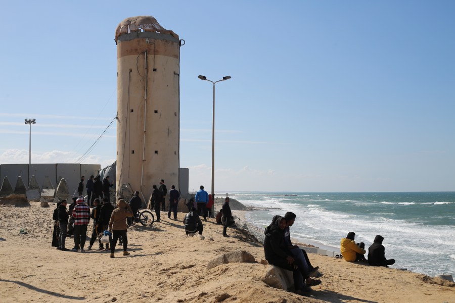 Palestinians displaced by the Israel air and ground offensive on the Gaza Strip sit next to the border fence with Egypt in Rafah, Wednesday, Jan. 24, 2024. (AP Photo/Hatem Ali)