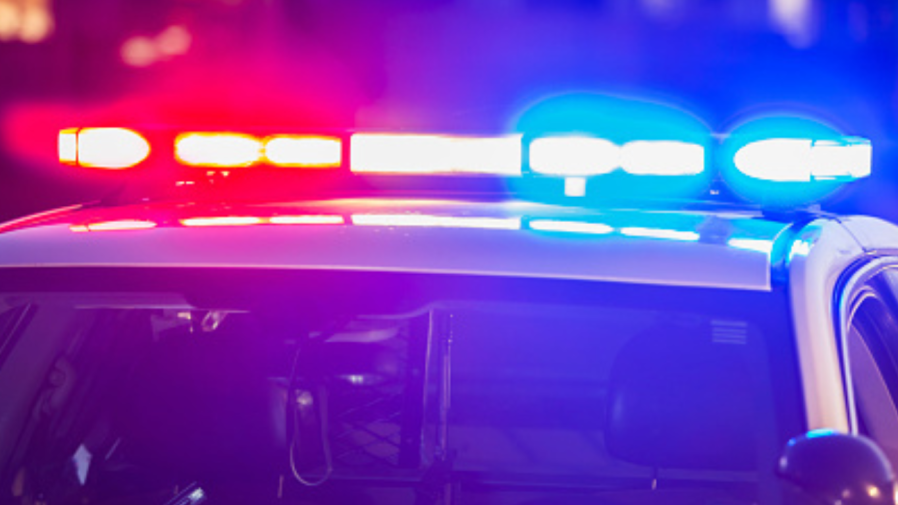 Red and blue lights flash on top of a police patrol car.