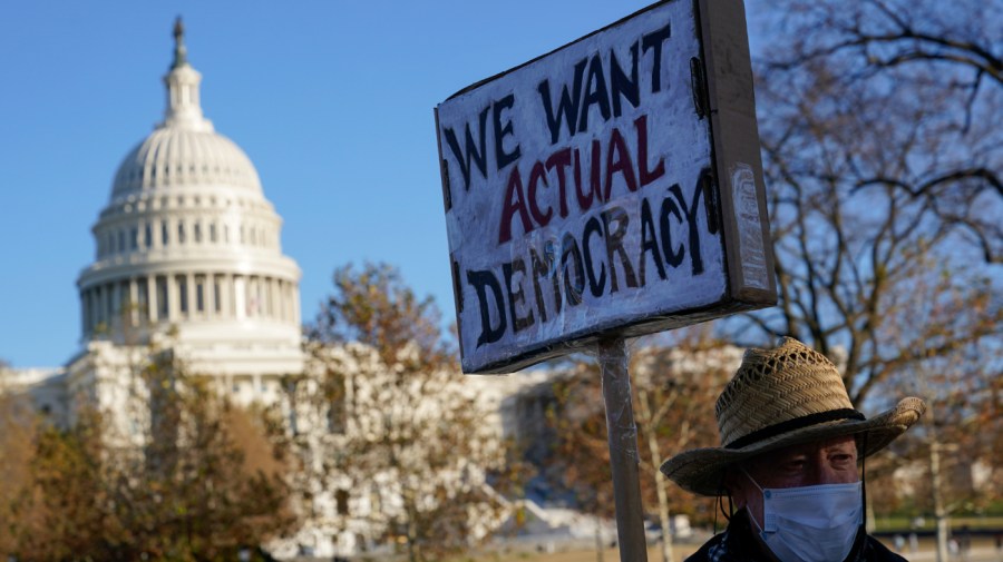 Protester David Barrows carries a sign during a rally to press Congress to pass voting rights protections and the "Build Back Better Act," Monday, Dec. 13, 2021, in Washington.