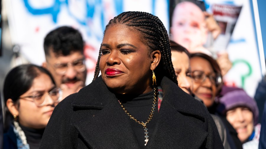 Representative Cori Bush is seen standing in front of a crowd of people at an event.