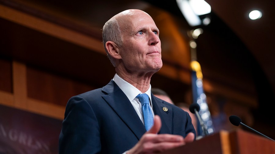 Senator Rick Scott speaks at a podium.