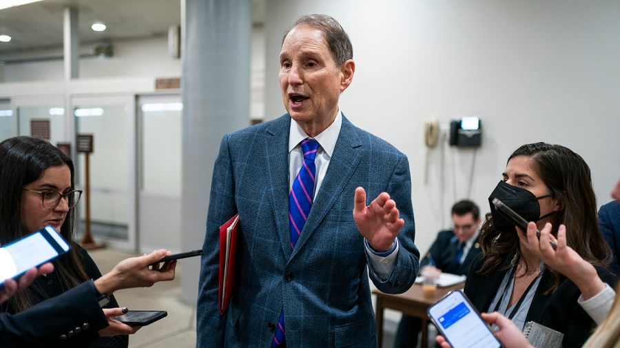 Senator Ron Wyden speaks to reporters gathered around him at the Capitol.