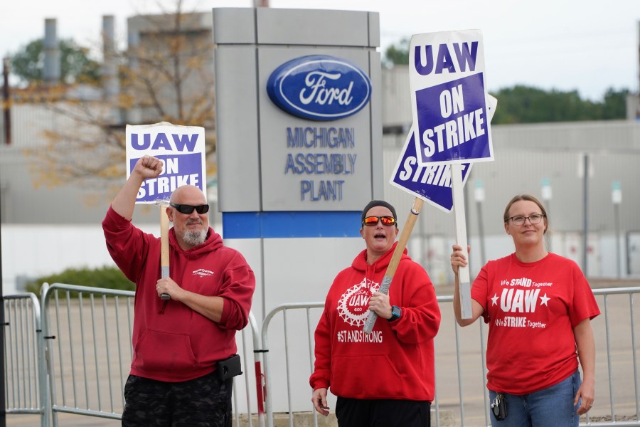 File - United Auto Workers members walk the picket line at the Ford Michigan Assembly Plant in Wayne, Mich., Sept. 26, 2023. Ford Motor Co. swung to a net loss in the fourth quarter due to a large accounting charge on pension plans and the effects of a six-week strike at multiple factories by the United Auto Workers union. (AP Photo/Paul Sancya, Ford)