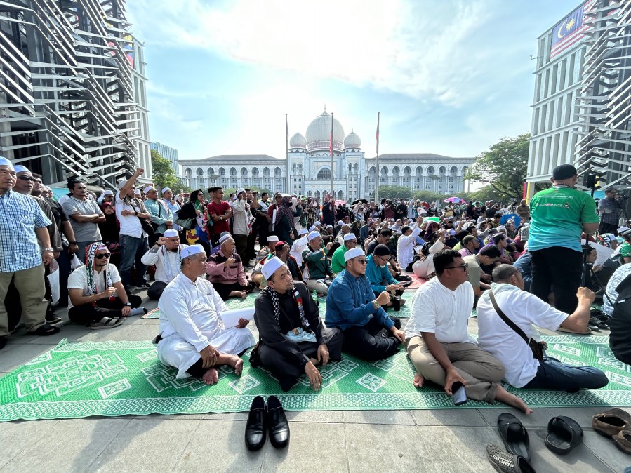 Members of the Pan-Malaysian Islamic Party wait outside the Palace of Justice, background, as they await the Federal Court's decision on Kelantan state's sharia law criminal enactment, in Putrajaya, Malaysia Friday, Feb. 9, 2024. Malaysia's top court Friday struck down over a dozen Shariah-based state laws, saying they encroached on federal authority, a decision denounced by Islamists who fear it could undermine religious courts across the country.(AP Photo)