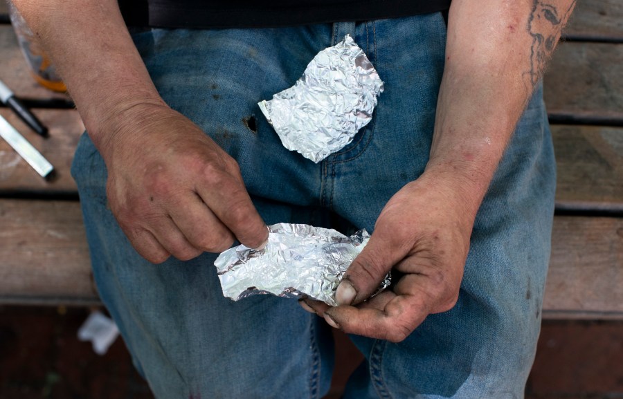 FILE - A man prepares to smoke fentanyl on a park bench in downtown Portland, Ore., on Thursday, May 18, 2023. Smoking has surpassed injecting as the most common way of taking drugs in U.S. overdose deaths, according to a study published by the Centers for Disease Control and Prevention on Thursday, Feb. 15, 2024. (Beth Nakamura/The Oregonian via AP, File)