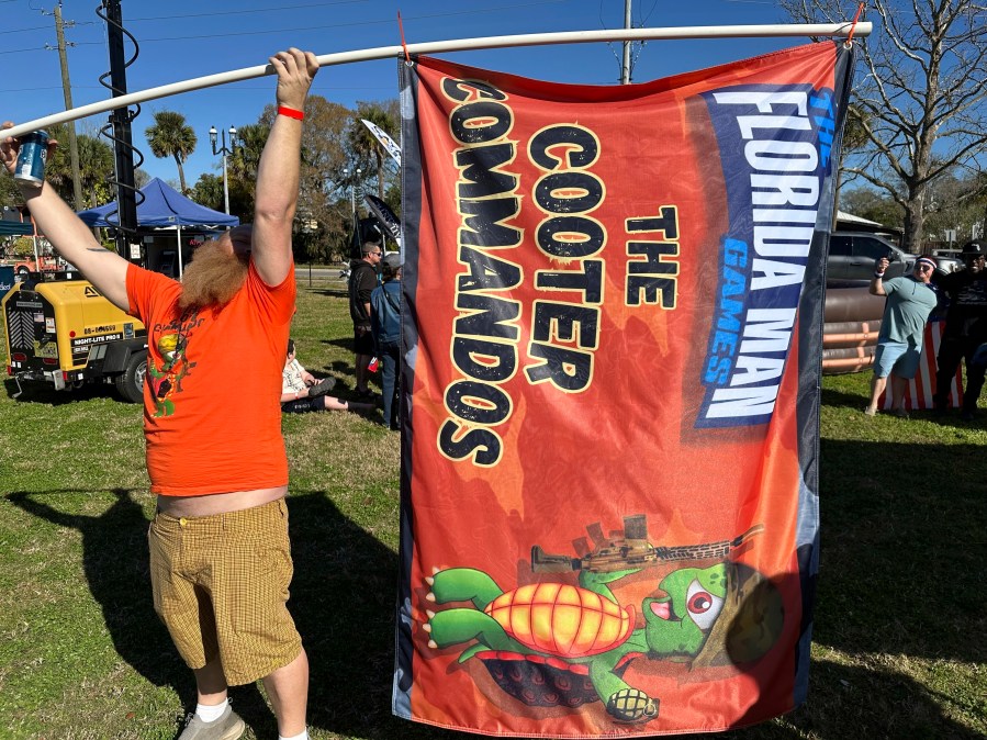 Andrew Peterson waves a flag for the team Cooter Commandos at the Florida Man Games on Saturday, Feb. 24, 2024, in St. Augustine, Fla. (AP Photo/Russ Bynum)