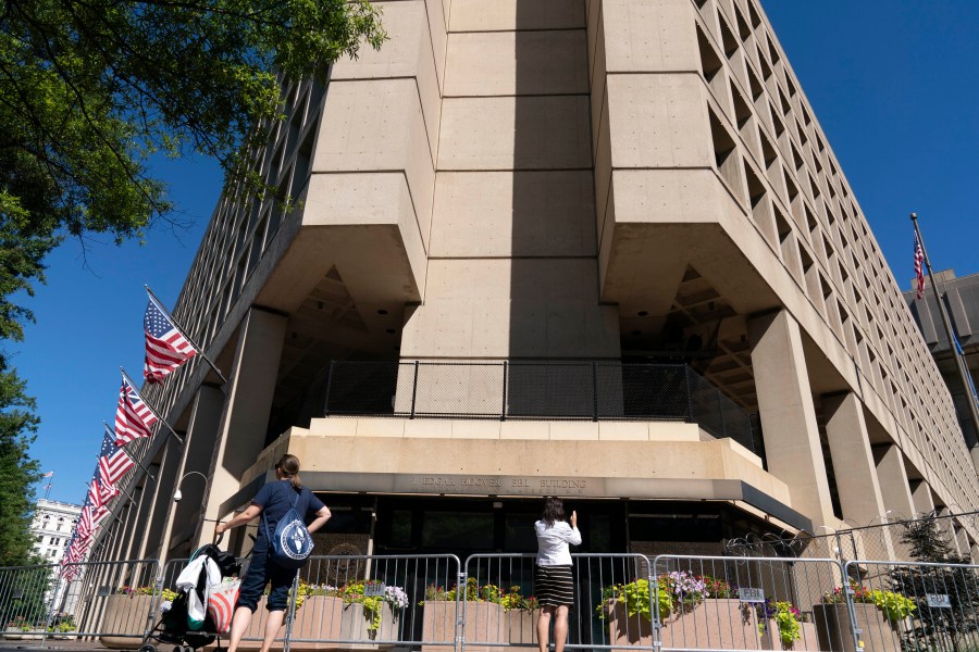 FILE - People take photos of the FBI building headquarters in Washington, Aug. 13, 2022. A federal judge has held veteran investigative reporter Catherine Herridge in civil contempt for refusing to divulge her source for a series of Fox News stories about a Chinese American scientist who was investigated by the FBI but never charged. (AP Photo/Jose Luis Magana, File)