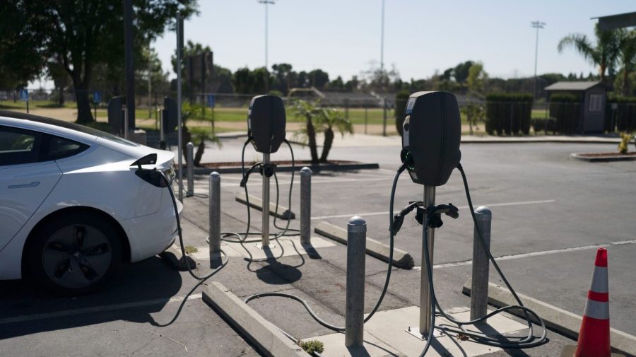 An electric car is plugged into a charger in a parking lot.