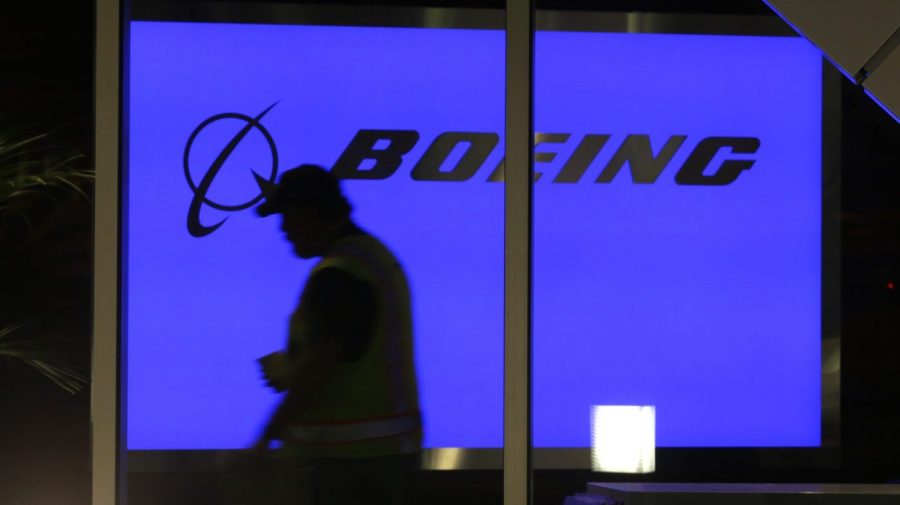 The silhouette of a person is seen walking into a blue Boeing sign.