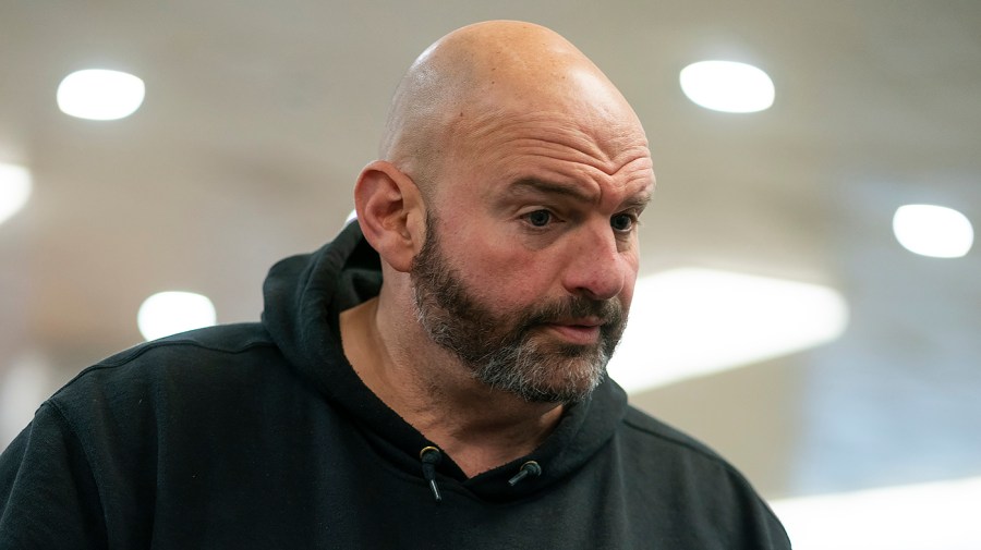 Senator John Fetterman speaks to reporters wearing his signature hoodie sweatshirt.