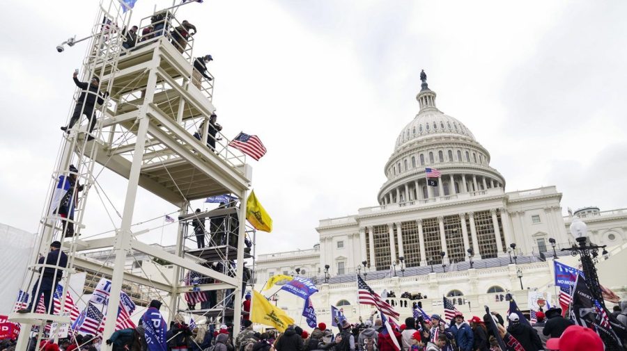 FILE - Violent insurrectionists loyal to President Donald Trump breach the U.S. Capitol in Washington, Jan. 6, 2021. John Banuelos, of Summit, Ill., who was accused of climbing scaffolding and firing a gun in the air during the riot was arrested Friday, March 8, 2024. Banuelos was charged with several felony and misdemeanor counts, including firearm charges. (AP Photo/John Minchillo, File)