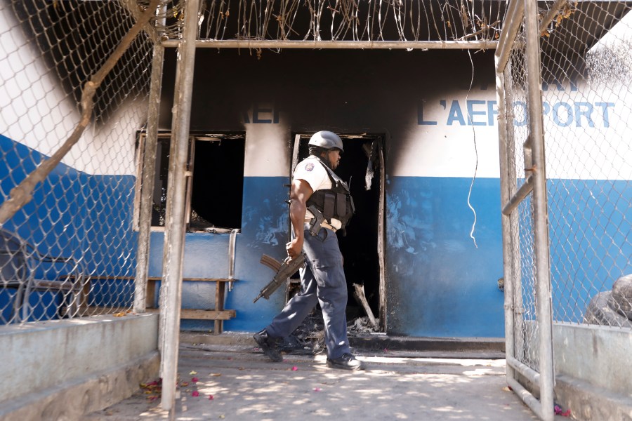 A police officer walks past a burnt out out police station set on fire by armed gangs, in Port-au-Prince, Haiti, Tuesday, March 5, 2024. (AP Photo/Odelyn Joseph)